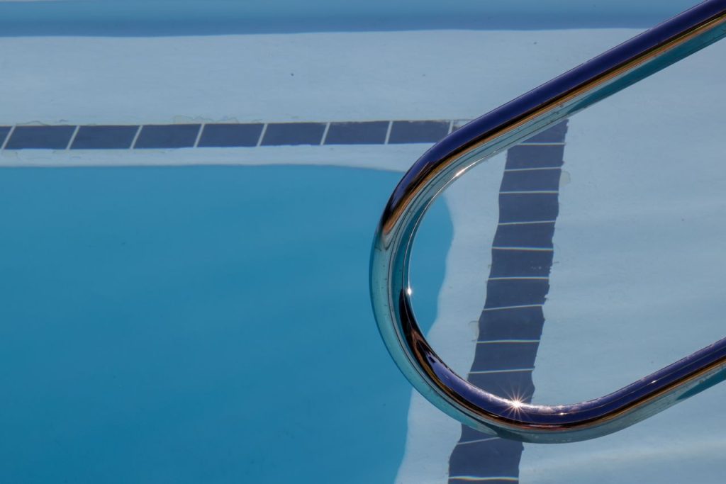 Mastering the First Impression: Your intriguing post title goes here Dynamic view of a swimming pool with ladder reflecting sunlight on the water surface.