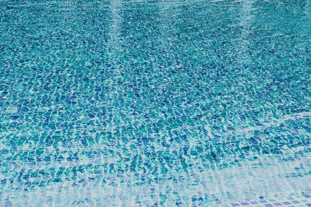Crafting Captivating Headlines: Your awesome post title goes here A close-up view of a swimming pool water surface with vibrant blue tiles creating a wavy pattern.